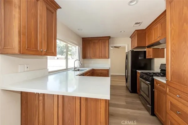 a kitchen with stainless steel appliances granite countertop a refrigerator a stove and a sink with wooden cabinets