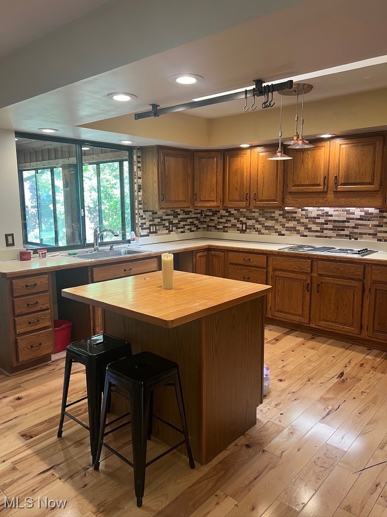 11331 Palmer Road Painesville, OH 44077 - Photo 11 of 47 Kitchen featuring a kitchen island, sink, light hardwood / wood-style floors, decorative light fixtures, and a kitchen breakfast bar