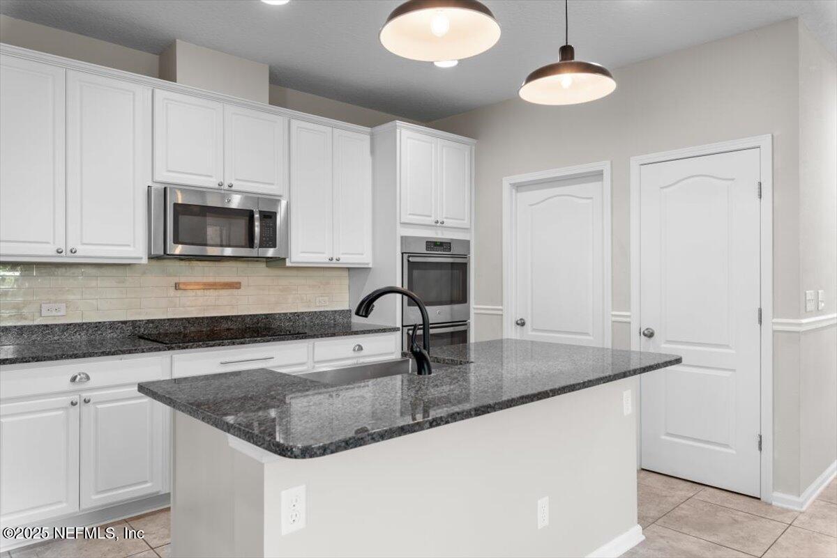 1011 Wetland Ridge Circle Middleburg, FL 32068 - Photo 13 of 73 a kitchen with granite countertop a sink a stove and cabinets