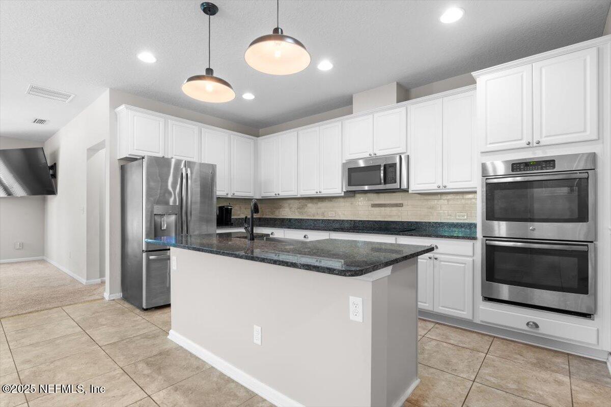 1011 Wetland Ridge Circle Middleburg, FL 32068 - Photo 16 of 73 a kitchen with stainless steel appliances granite countertop a stove a refrigerator and a microwave