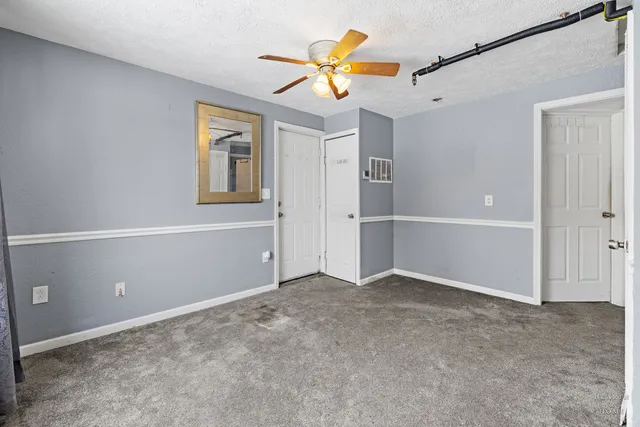 an empty room with closet and a ceiling fan