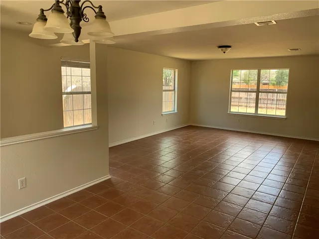 a view of an empty room with glass door and windows