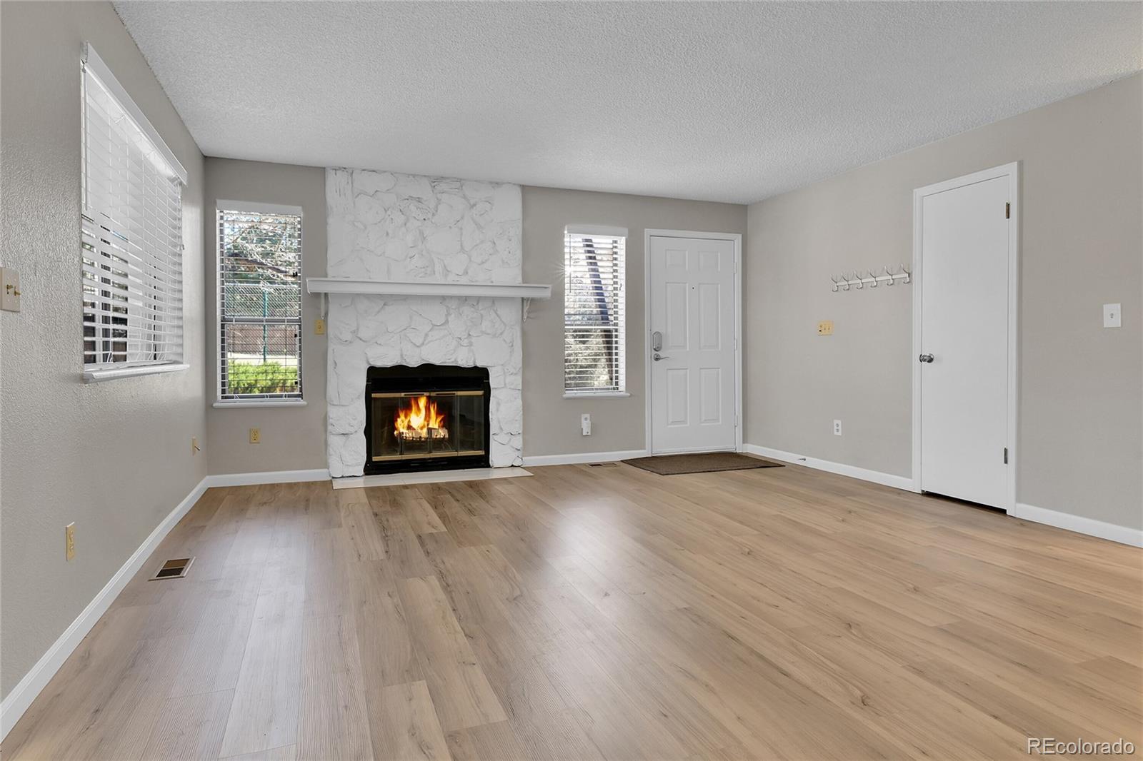 9501 West 89th Circle Broomfield, CO 80021 - Photo 3 of 33 an empty room with wooden floor fireplace and windows