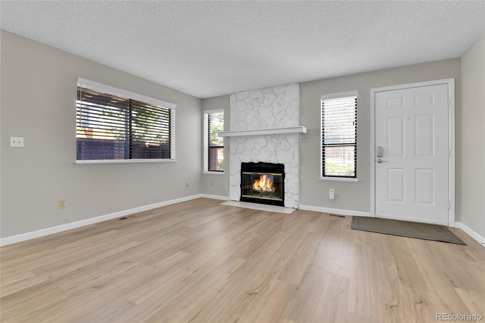 9501 West 89th Circle Broomfield, CO 80021 - Photo 4 of 33 an empty room with wooden floor fireplace and windows