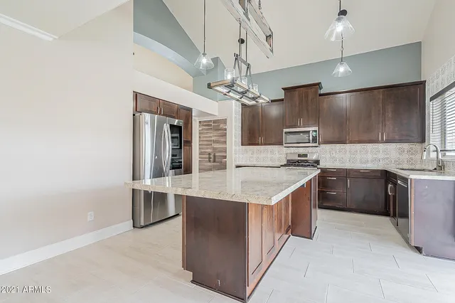 a kitchen with kitchen island granite countertop a sink appliances cabinets and furniture
