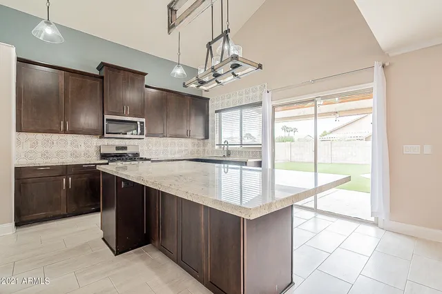 a kitchen with kitchen island granite countertop a sink stove and refrigerator