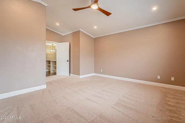 an empty room with closet and a ceiling fan
