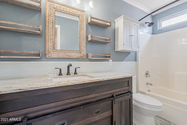 a bathroom with a granite countertop sink a toilet a vanity and shower