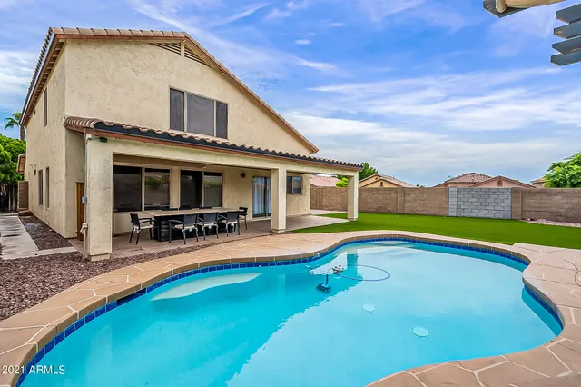 a view of swimming pool with outdoor seating and house in the background