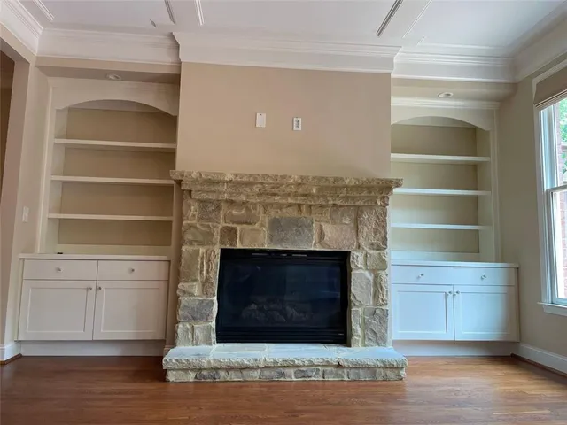 a view of an empty room with wooden floor and chandelier