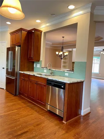 a kitchen with stainless steel appliances granite countertop wooden cabinets a sink a stove a refrigerator and island with wooden floor