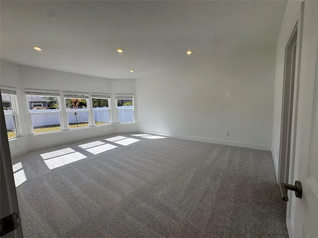 an empty room with shelves and view of kitchen