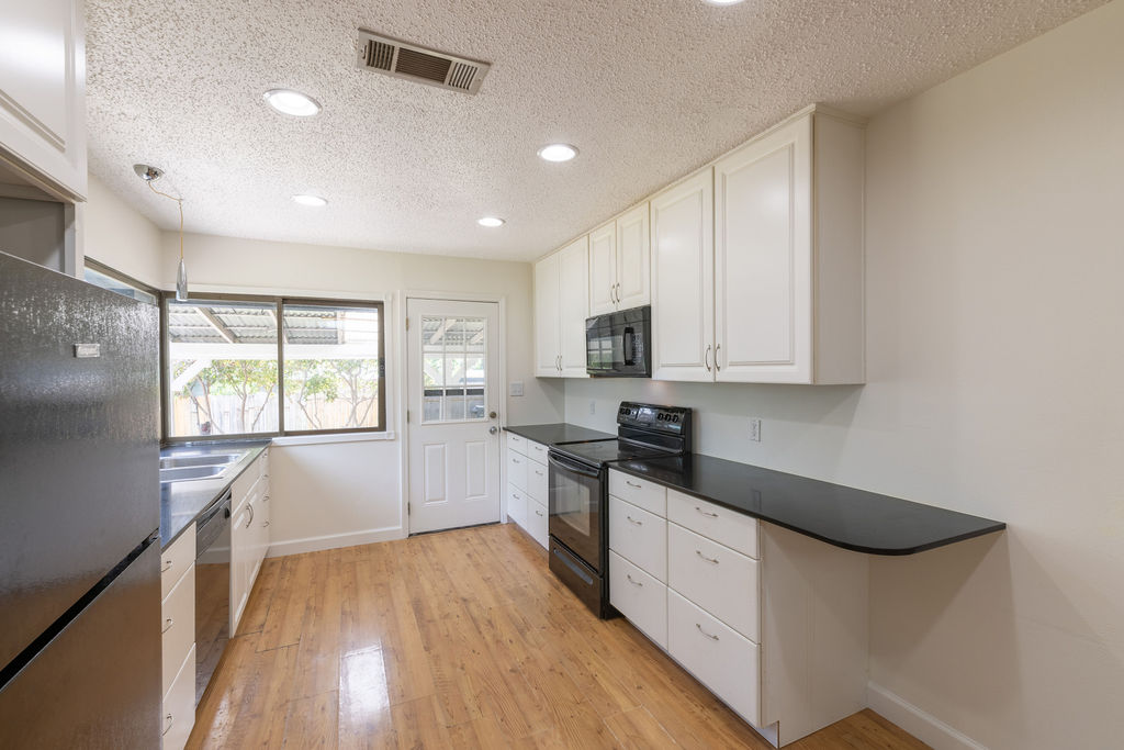 5310 Presidio Road Austin, TX 78745 - Photo 4 of 34 A well-equipped kitchen features ample cabinetry and dark countertops, alongside durable hardwood flooring.