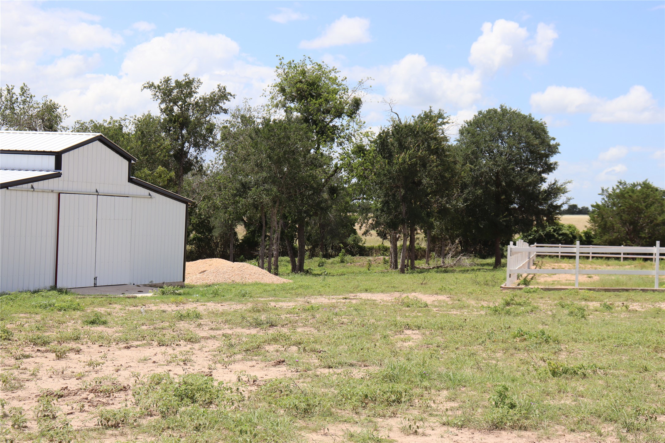 1220 Brushy Branch Road Lockhart, TX 78644 - Photo 13 of 14 A well-maintained barn offers ample storage, set against a backdrop of mature trees and open fields.