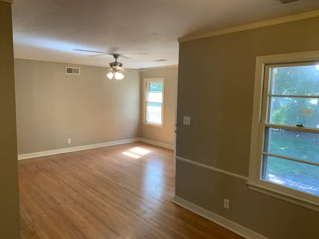an empty room with wooden floor and windows