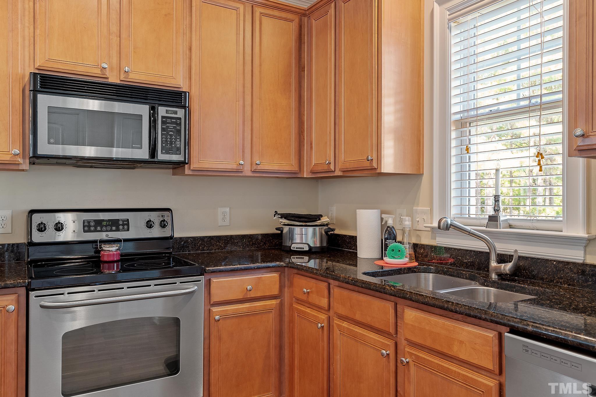 7708 Alexander Promenade Place Raleigh, NC 27617 - Photo 13 of 27 a kitchen with stainless steel appliances granite countertop a sink a stove a microwave and cabinets