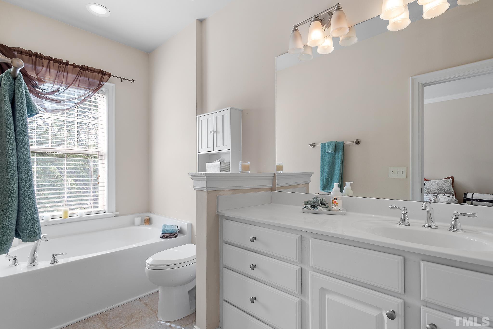 7708 Alexander Promenade Place Raleigh, NC 27617 - Photo 25 of 27 a bathroom with a granite countertop sink a toilet a mirror a vanity a bathtub and shower