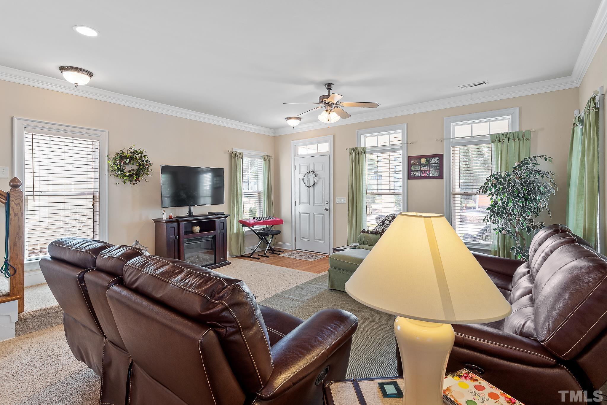 7708 Alexander Promenade Place Raleigh, NC 27617 - Photo 7 of 27 a living room with furniture a fireplace and a flat screen tv