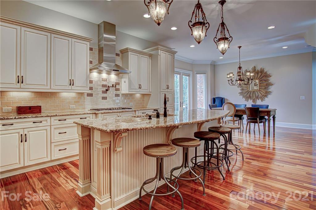 2105 South Wendover Road Charlotte, NC 28211 - Photo 13 of 46 a kitchen with granite countertop a table chairs stove and white cabinets