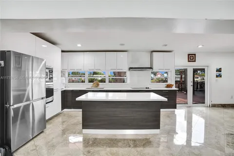 a large kitchen with stainless steel appliances kitchen island granite countertop a table chairs refrigerator and a sink