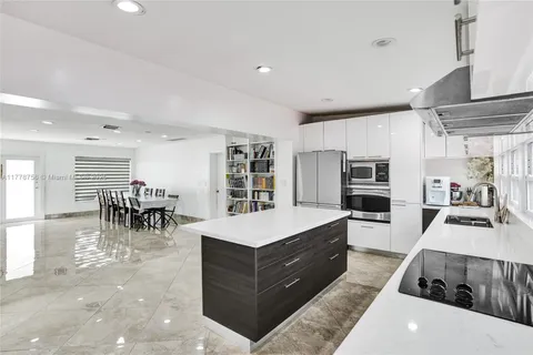 a large white kitchen with lots of counter top space and stainless steel appliances