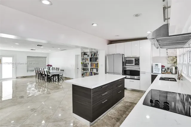 a large white kitchen with lots of counter top space and stainless steel appliances