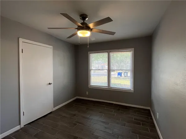 an empty room with wooden floor fan and windows