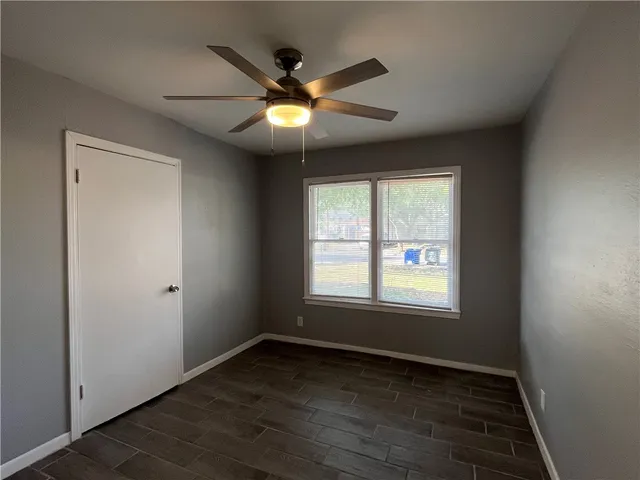 an empty room with wooden floor fan and windows