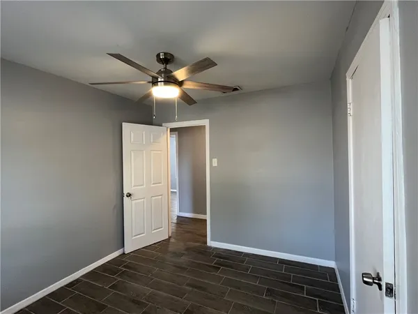 a view of an empty room with window and chandelier fan