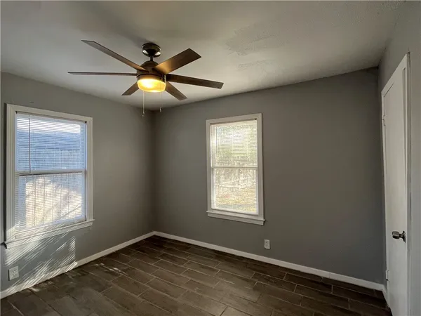 an empty room with wooden floor closet and windows