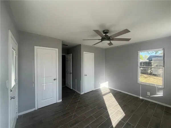 a view of an empty room with wooden floor and a window