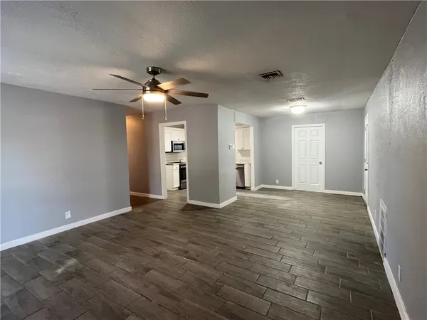 a view of an empty room with chandelier fan and a fireplace