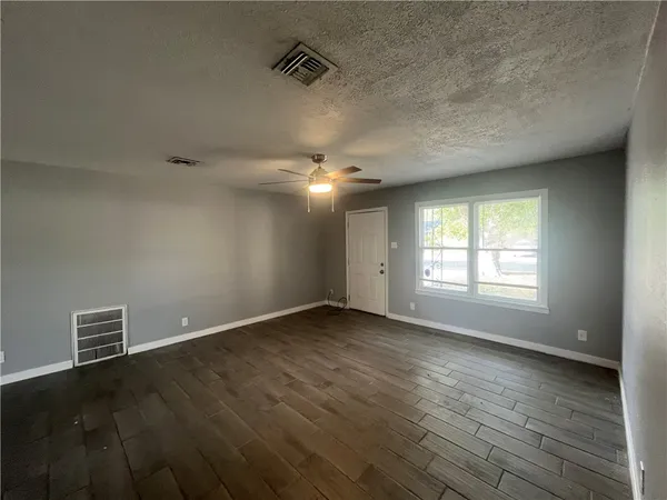 an empty room with wooden floor and windows