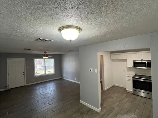an empty room with wooden floor cabinet and windows