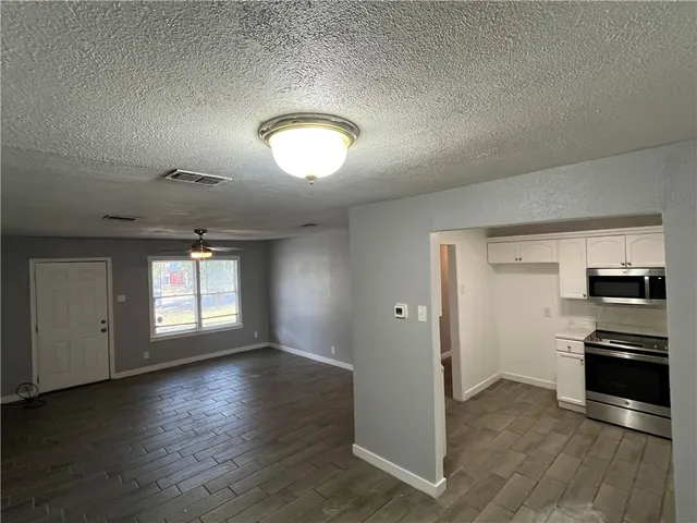 an empty room with wooden floor cabinet and windows