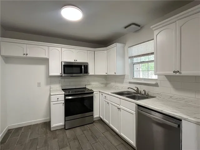 a kitchen with granite countertop stainless steel appliances a stove cabinets and a window