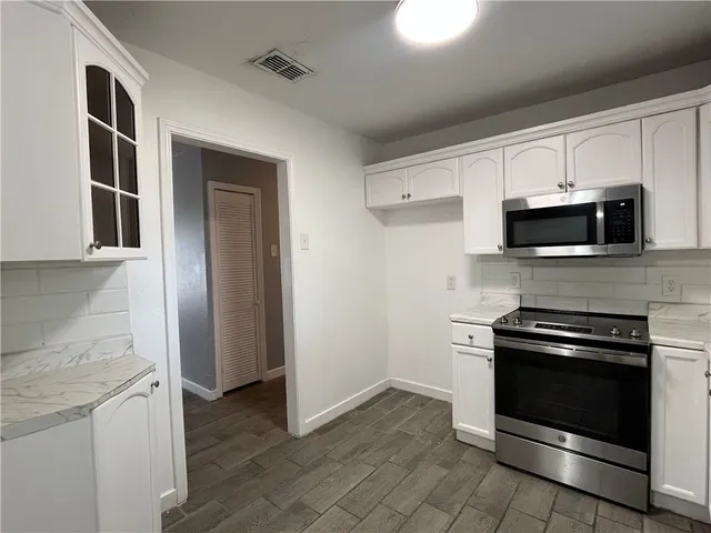 a kitchen with granite countertop a stove and a microwave