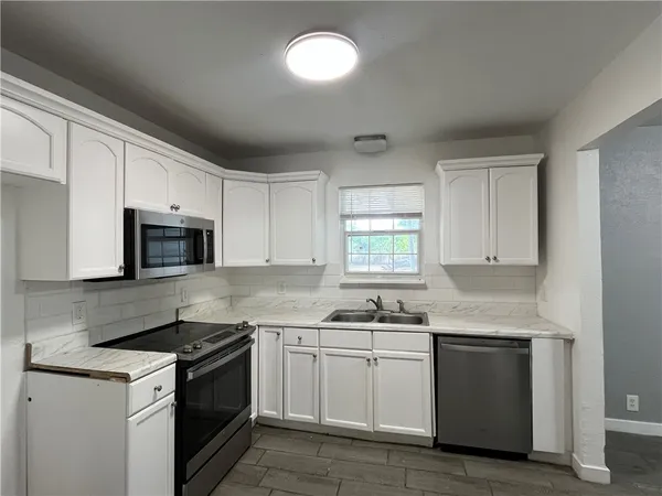 a kitchen with granite countertop white cabinets and stainless steel appliances