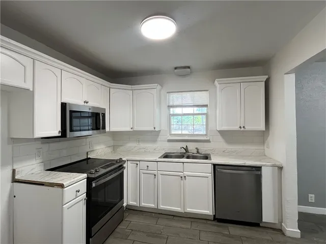 a kitchen with granite countertop white cabinets and stainless steel appliances