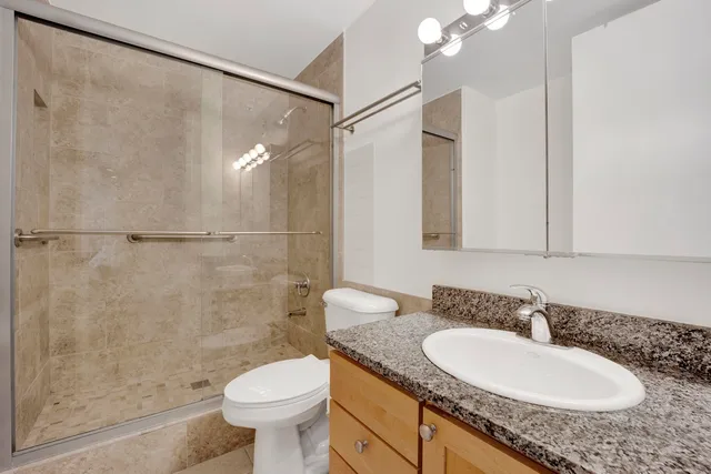 a bathroom with a granite countertop sink toilet and shower