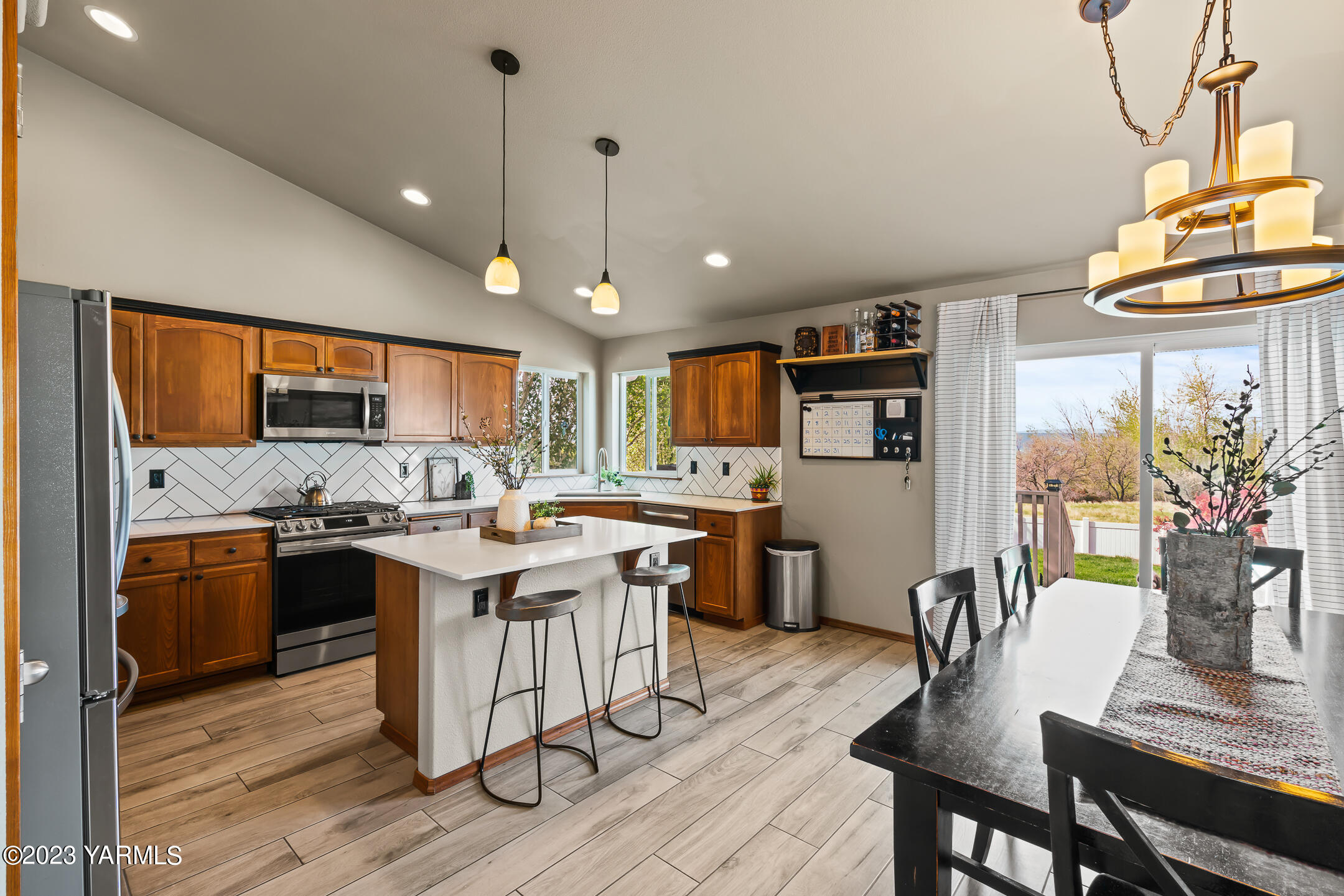4702 Goat Rocks Court Yakima, WA 98901 - Photo 8 of 36 a kitchen with stainless steel appliances granite countertop a stove a refrigerator a kitchen island a dining table and chairs with wooden floor