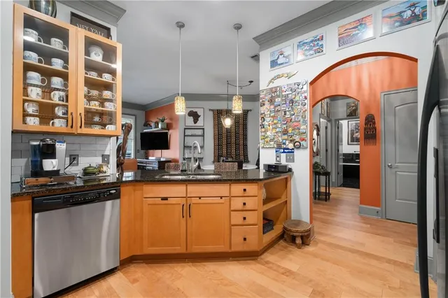 a kitchen with stainless steel appliances granite countertop a stove top oven a sink dishwasher and cabinets with wooden floor