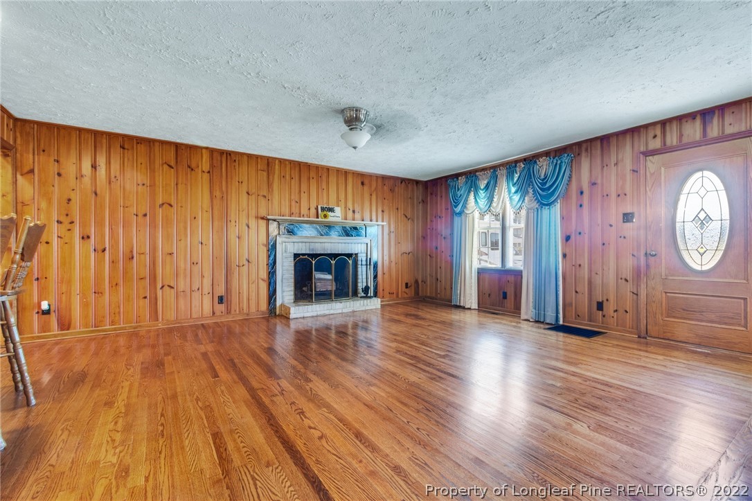5457 Sambo Jackson Road Godwin, NC 28344 - Photo 13 of 33 an empty room with wooden floor fireplace and windows