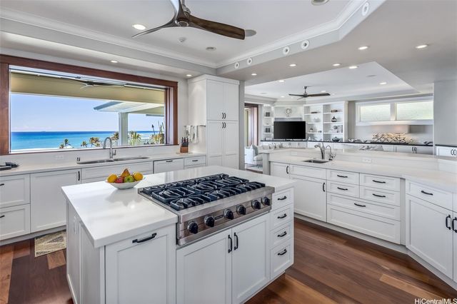 a kitchen with stainless steel appliances kitchen island wooden floors and white cabinets