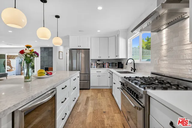 a kitchen with stainless steel appliances granite countertop a stove a sink and a refrigerator