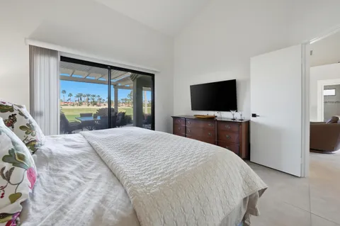 a bedroom with a bed and a flat tv screen on dresser