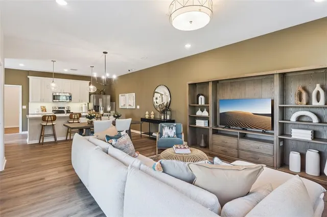 a living room with furniture kitchen view and a wooden floor