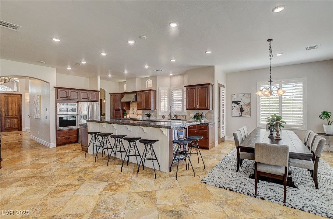 1182 Thomas Bay Circle Logandale, NV 89021 - Photo 21 of 98 Kitchen featuring a chandelier, a kitchen bar, a spacious island, arched walkways, and recessed lighting
