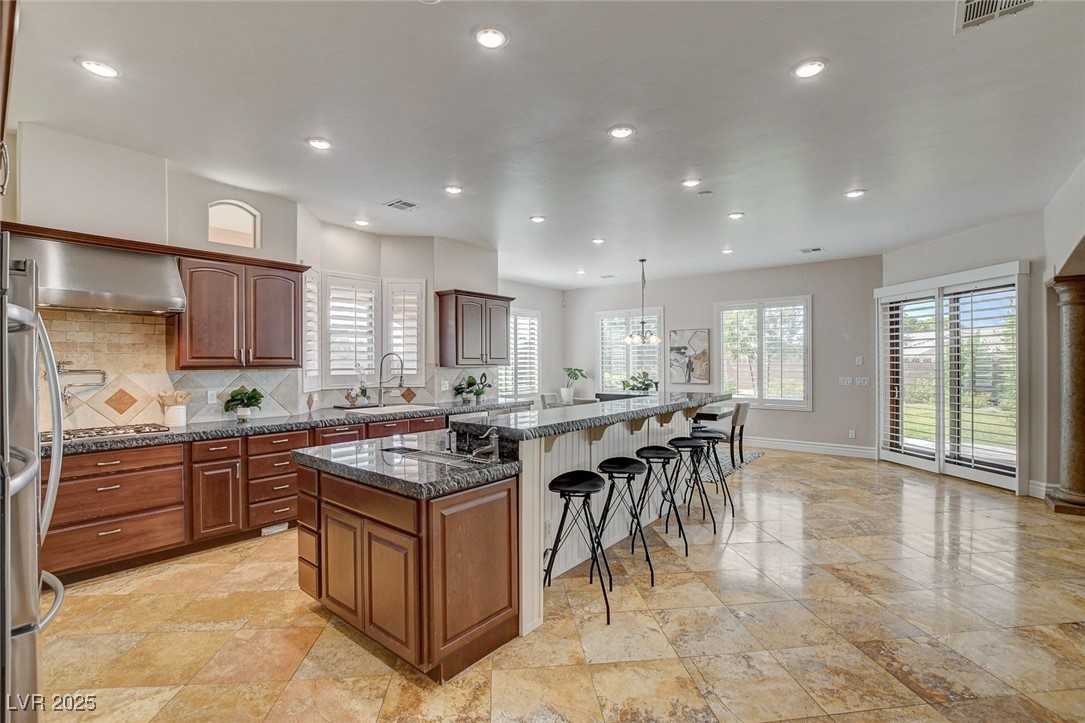 1182 Thomas Bay Circle Logandale, NV 89021 - Photo 25 of 98 Kitchen with a kitchen island, a breakfast bar, wall chimney range hood, recessed lighting, and backsplash