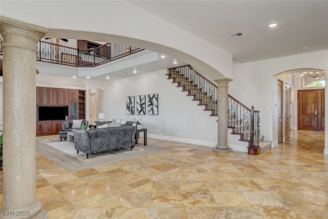 1182 Thomas Bay Circle Logandale, NV 89021 - Photo 32 of 98 Living room featuring arched walkways, a high ceiling, stairs
